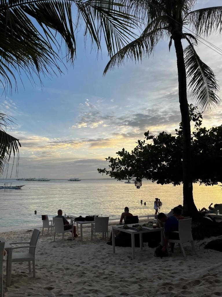 Seaside dining setup under palm trees at dusk in Malapascua Island, Cebu