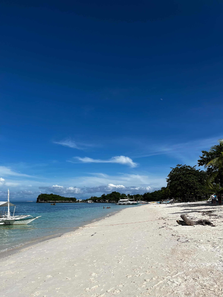 Pristine white sand beach with turquoise water and outrigger boats in Malapascua